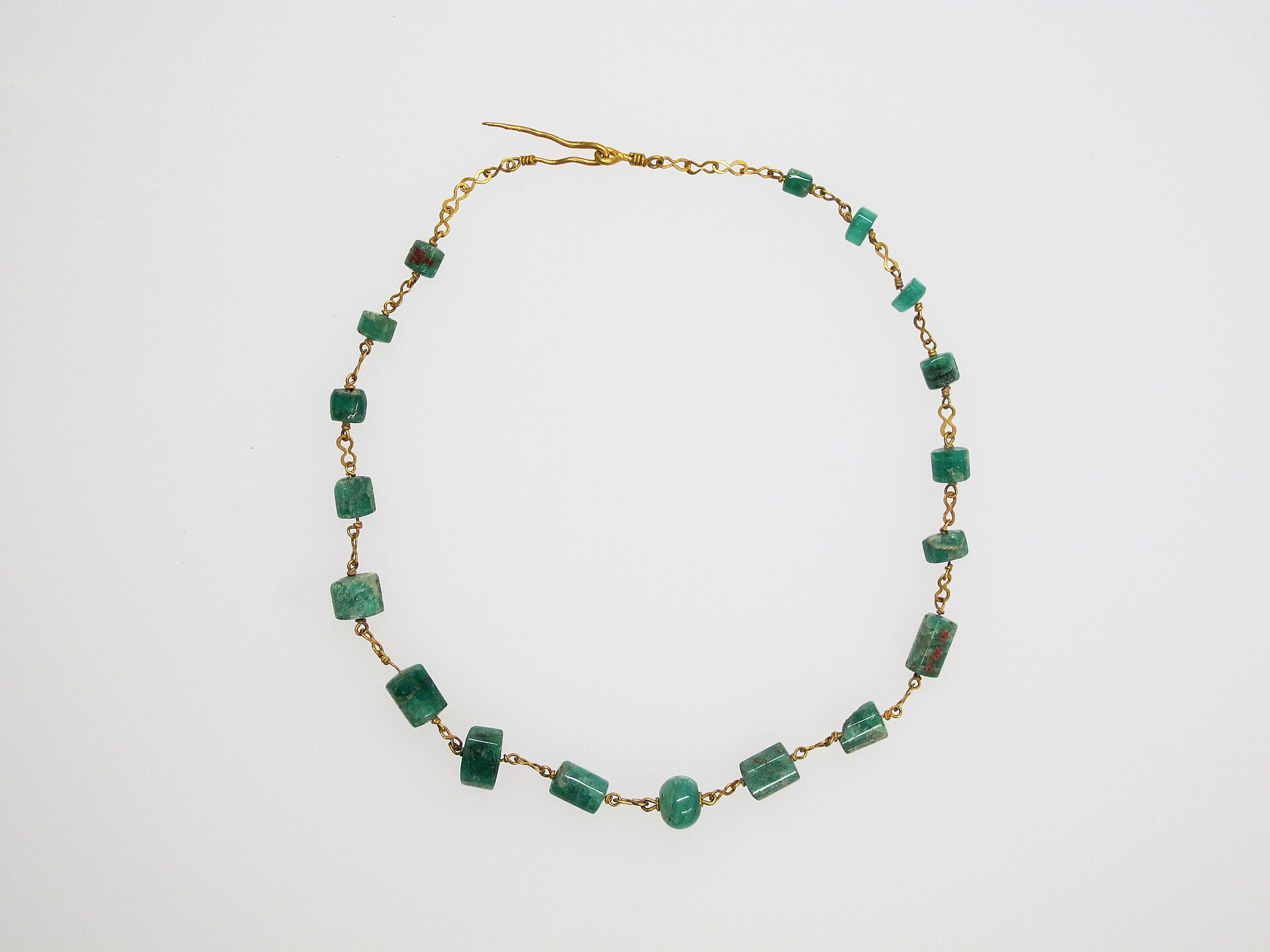 Gold necklace with emerald beads laid in a circle